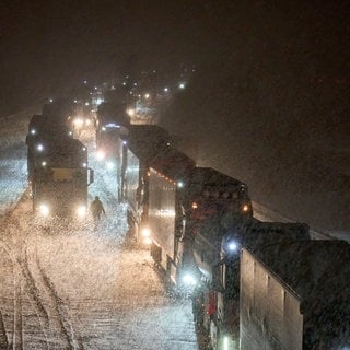 Auf der A3 im Westerwald stehen bei Schnee viele Lkw im Stau.