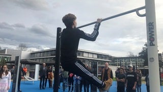 Toben und turnen statt Handy in der Pause: Ein Junge zieht sich an einem neuen Reck auf dem Schulhof der Barbarossaschule in Sinzig hoch. 