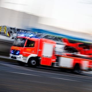 Ein Einsatzfahrzeug der Feuerwehr fährt mit Blaulicht und Martinshorn zu einem Einsatz. Im Industriegebiet in Adenau ist ein Brand ausgebrochen. 