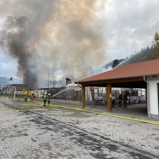 Feuerwehrleute bekämpfen den Brand bei einem Baustoffhandel in Adenau