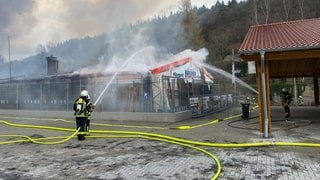 Feuerwehrleute löschen in Adenau das Feuer auf dem Gelände eines Baustoffhandels