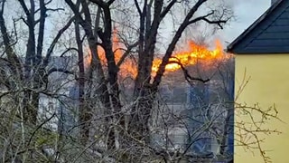 Aus dem Dachgeschoss des Mehrfamilienhauses in Neuwied schlagen die Flammen lichterloh. Die Feuerwehr hat den Großbrand inzwischen unter Kontrolle. 