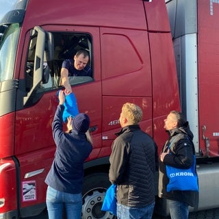 Mitarbeiter eines Charity-Vereins verteilen kleine Weihnachtsgeschenke an ausländische Lastwagenfahrer auf der A61