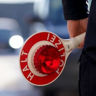 Ein Polizist hält eine Anhaltekelle in der Hand.