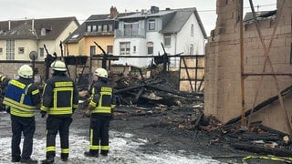 Feuerwehrleute begehen den Brandort in Engers am Neujahrstag