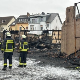 Feuerwehrleute begehen den Brandort in Engers am Neujahrstag