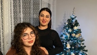 Zara Malyan und ihre Mutter Syuzanna Andreasyan vor einem festlich geschmückten Weihnachtsbaum. Die Familie aus Armenien feiert am 6. Januar Weihnachten.