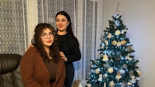 Zara Malyan und ihre Mutter Syuzanna Andreasyan vor einem festlich geschmückten Weihnachtsbaum. Die Familie aus Armenien feiert am 6. Januar Weihnachten.