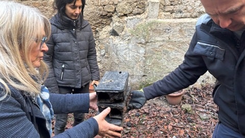 Ein Schädlingsbekämpfer übergibt Rattenfallen an Anwohnerinnen aus Andernach