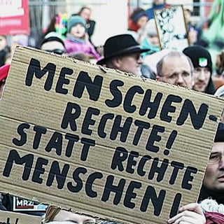 Menschen in Koblenz halten Schilder mit Parolen gegen Rechtsextremismus hoch