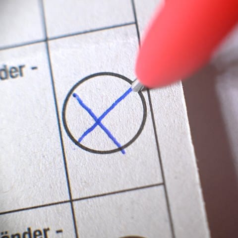 Mit einem Kuli wird auf einem Wahlzettel ein Kreuz gemacht