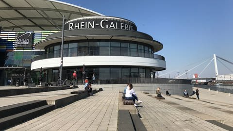 Leute sitzen auf Abstand vor der Rhein-Galerie in Ludwigshafen