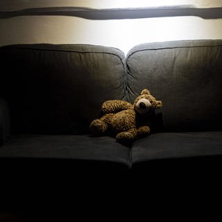 teddybear auf couch in dunklem Zimmer