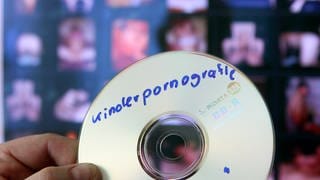 Ein Fahnder des Landeskriminalamtes hält eine CD mit kinderpornografischem Material in der Hand.
