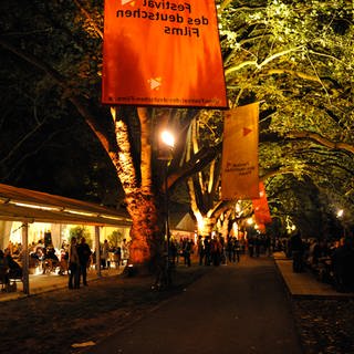 Filmfestival-Gelände am Abend mit Zelten und Bänken unter den Platanen auf der Parkinsel