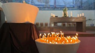 Kerzen brennen in der Christ König Kirche, die bei der Gedenkandacht für die Opfer der Messerattacke in Oggersheim angezündet wurden.