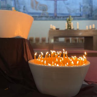 Kerzen brennen in der Christ König Kirche, die bei der Gedenkandacht für die Opfer der Messerattacke in Oggersheim angezündet wurden.