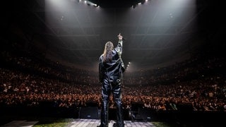 Der Rapper Apache 207 auf der Bühne vor großem Publikum bei einem Konzert