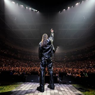 Der Rapper Apache 207 auf der Bühne vor großem Publikum bei einem Konzert