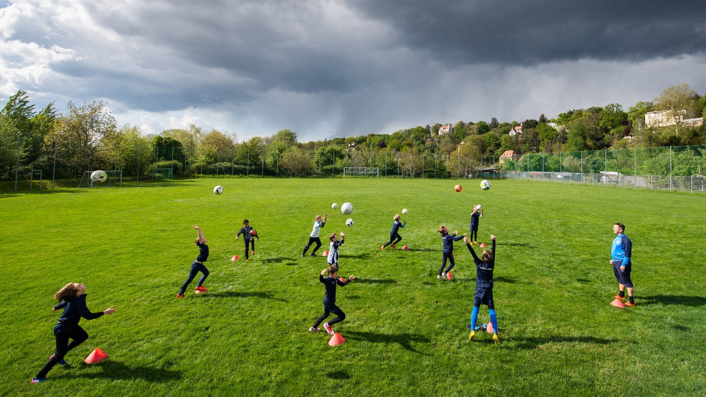 Kinder trainieren Fußball auf einem Sportplatz.