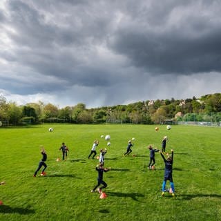 Kinder trainieren Fußball auf einem Sportplatz. 