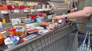 Kundin legt in Supermarkt Waren auf ein Band - Symbolbild zu Diebstahlserie in Supermarkt in Ludwigshafen