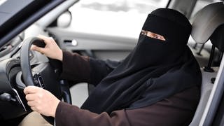 Eine Frau mit Niqab sitzt am Steuer eines Autos. Das Verwaltungsgericht Neustadt hat einer Muslimin genau das jetzt verboten.