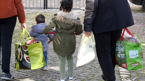 Eine Familie nach dem Besuch einer Tafel. In den Händen halten sie Plastiktüten mit Lebensmitteln.