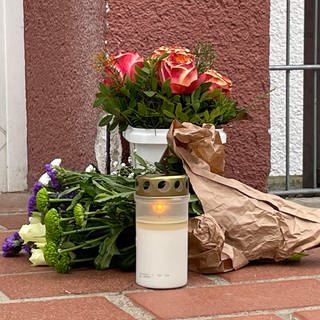 Blumen und eine Kerze vor einer Kita in Limburgerhof erinnern an das tote Kind