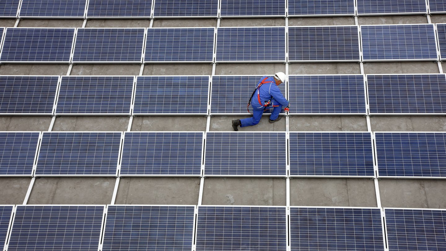 Monteur auf Solarfläche auf Flachdach. Symbolbild für Ludwigshafen investiert 7,5 Millionen Euro in Klima-Projekte