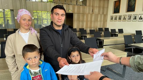 Eine Familie aus der Türkei bekommt im Rhein-Pfalz-Kreis eine Bezahlkarte ausgehändigt.