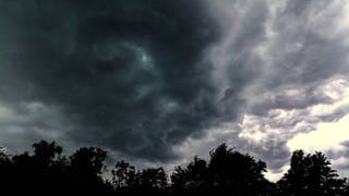 Dunkle Gewitterwolken ziehen über Bäume (Symbolbild)