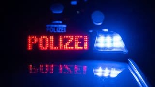 Polizisten vor einem Polizeifahrzeug (Symbolbild): Auf der A6 bei Frankenthal stießen ein Auto und ein Motorrad zusammen