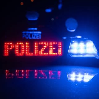 Polizisten vor einem Polizeifahrzeug (Symbolbild): Auf der A6 bei Frankenthal stießen ein Auto und ein Motorrad zusammen