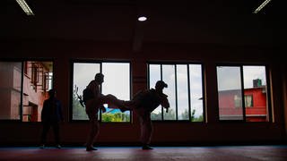 Zwei Menschen machen Taekwondo in einer Halle.