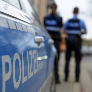 Zwei Polizisten mit Einsatzwagen 