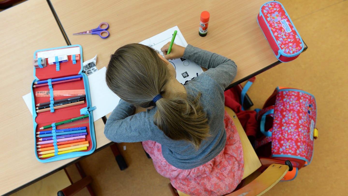 Schülerin sitzt über ihren Aufgaben in einer Schule: Symbolbild für Ludwigshafen muss seine Grundschulen für den Ganztagsbetrieb ausbauen