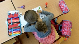 Schülerin sitzt über ihren Aufgaben in einer Schule: Symbolbild für Ludwigshafen muss seine Grundschulen für den Ganztagsbetrieb ausbauen 