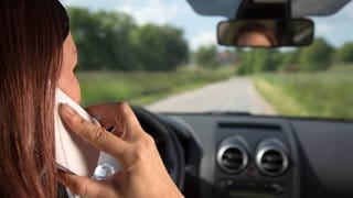 Eine Frau fährt mit Handy am Steuer: In der Pfalz waren bei Verkehrskontrollen laut Polizei viele Fahrer abgelenkt.