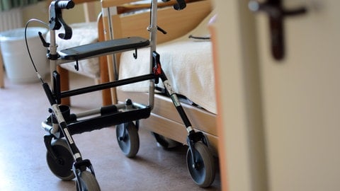 Ein Rollator steht vor einem Pflegebett