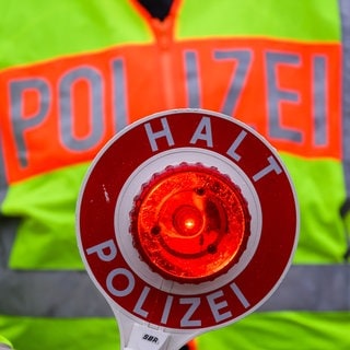 Eine Polizeikelle während einer Verkehrskontrolle. Autofahrer nehmen verbotene Abkürzungen für die gesperrte B9.