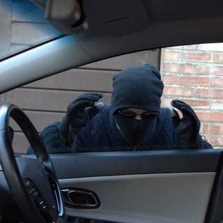 Autodieb, der mit der Absicht zu stehlen durch ein Autofenster schaut. Symbolbild dafür, dass ein Dieb in Grünstadt einen teuren Jeep gestohlen hat.