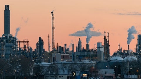 Rauchende Schornsteine der BASF in Ludwigshafen vor rötlichem Himmel. Auch im nördlichen Teil der Pfalz soll es bald Geothermie geben.