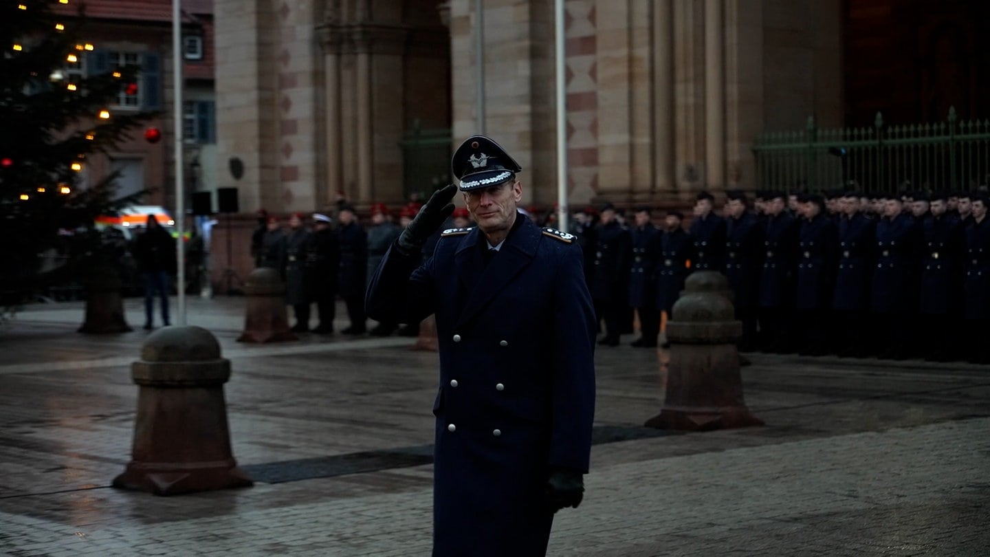 Ein Bundeswehrsoldat beim Gelöbnis vor dem Speyerer Dom salutiert. Im Hintergrund stehen zahlreiche Rekruten.