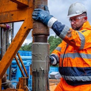 Ein Arbeiter mit einem Bohrgestänge auf einer Geothermie-Anlage