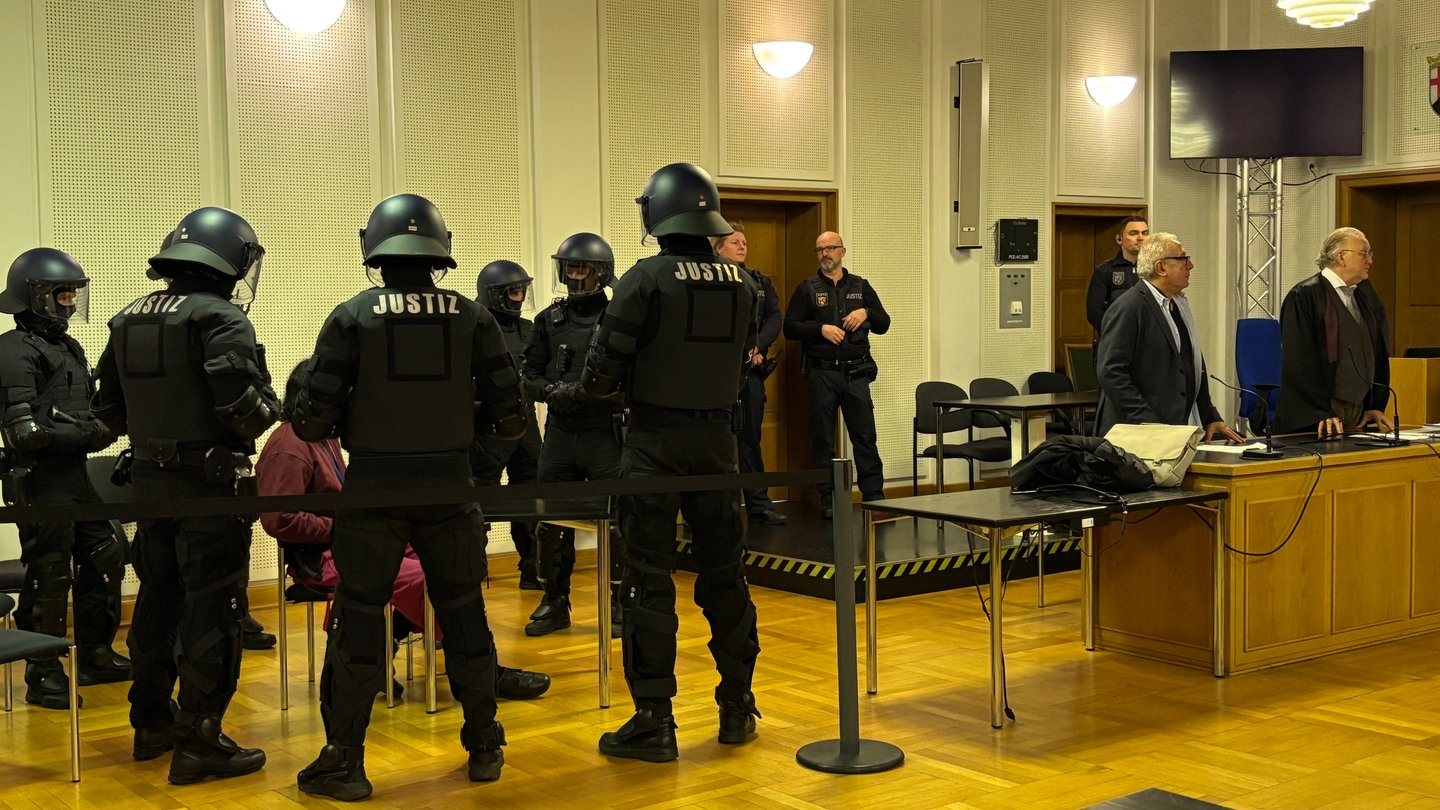 Der Mann, der einen JVA-Beamten niedergestochen haben soll, steht im Gerichtssaal in Frankenthal unter schwerer Bewachung