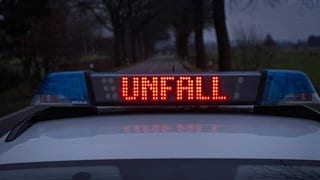 Ein Einsatzfahrzeug, Streifenwagen der Polizei steht bei einem Verkehrsunfall mit Blaulicht und dem Schriftzug, Unfall, im Display auf einer Landstraße.