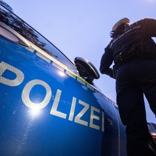 Eine Polizistin steht an einem Polizeiauto (Symbolbild). 