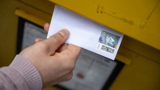 Eine Hand wirft einen Brief in einen gelben Post-Briefkasten. Fünf Bandenmitglieder stehen wegen Betrugs mit geklauten Rechnungen im Februar vor Gericht. 