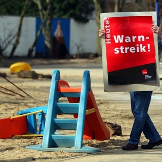 Mann hängt Bild in Kita auf für Warnstreik, Symbolbild für Streiks in der Pfalz